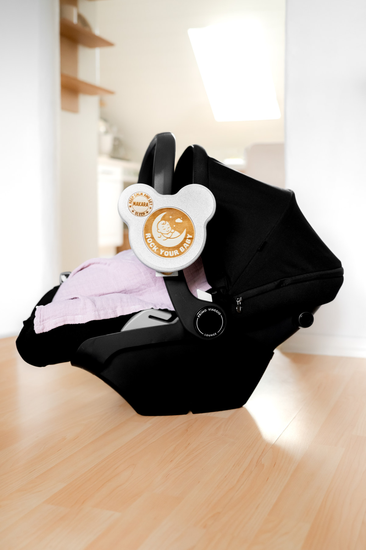 ROCK your BABY an einer Babyschale in heller Wohnumgebung.